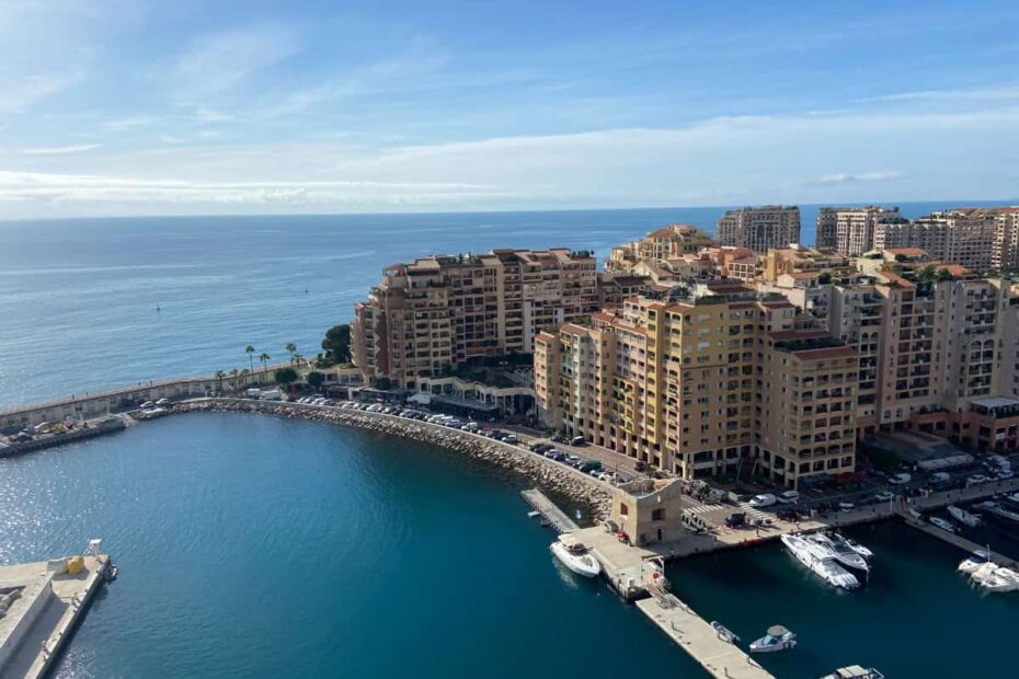View of Monaco with buildings along the shore and a pier reaching out into the blue waters of the French Riviera, Cote d'Azur